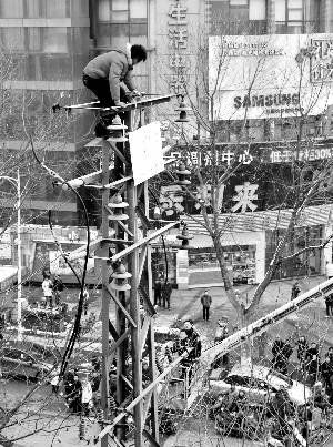 男子因经济纠纷爬上闹市高压线杆讨说法(组图)